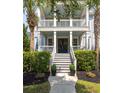 Elegant home entrance with a staircase to the porch, flanked by palm trees and lush greenery at 4073 Blackmoor St, Mount Pleasant, SC 29466