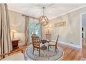 Chic dining area featuring hardwood floors, round rug, and a glass-topped table near sunlit French doors at 183 Civitas St, Mount Pleasant, SC 29464