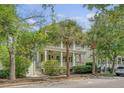 Two-story home featuring double porches, mature trees, and an American flag creating a welcoming facade at 183 Civitas St, Mount Pleasant, SC 29464
