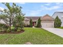 Beautiful exterior with a lush green lawn, mature trees, stone accents, and a two-car garage at 193 Cypress Forest Dr, Moncks Corner, SC 29461