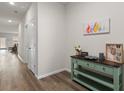 Bright hallway with wood floors, white doors, console table with decor and colorful artwork at 215 Cypress Plantation Rd, Moncks Corner, SC 29461