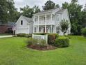 Two-story house featuring a manicured lawn, vibrant greenery, and a charming white picket fence at 605 Pointe Of Oaks Rd, Summerville, SC 29485