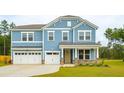 Charming two-story home with blue siding, stone accents, three-car garage, and well-manicured lawn at 735 Breakers Reef Ln, Huger, SC 29450