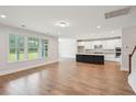 Open-concept living room with hardwood floors, and a view of the modern kitchen and backyard at 735 Breakers Reef Ln, Huger, SC 29450