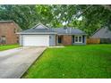 Inviting single-story home with a lush lawn, attached garage, and brick-accented entrance at 105 Glebe Rd, Summerville, SC 29485