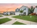 A row of homes featuring blue and gray siding, a spacious driveway, and a well-manicured lawn at 141 Pine Crest View Dr, Summerville, SC 29486