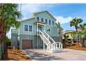 Charming beach house with a private garage, lush landscaping, and a welcoming stairway to the entrance at 313 E Arctic Ave, Folly Beach, SC 29439