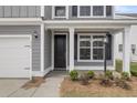 Close-up of a home's entrance featuring a black door, white trim, and manicured landscaping at 357 Hillman Trail Dr, Moncks Corner, SC 29461