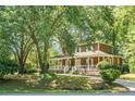 Charming two-story home featuring a wide front porch with white railings, brick accents, and mature landscaping at 49 Crosscreek Dr, Charleston, SC 29412