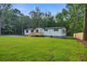 Inviting one-story home with a wooden deck and landscaped lawn nestled in a serene wooded area, offering privacy at 117 Dairy Ln, Cottageville, SC 29435