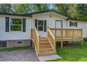 Welcoming exterior with a wooden deck and staircase leading to the entrance, set against a backdrop of lush greenery at 117 Dairy Ln, Cottageville, SC 29435