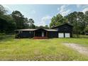 Charming dark home with an attached two-car garage, complemented by a lush green lawn at 1211 Lem Rd, Cordesville, SC 29434