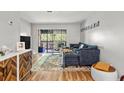 Comfortable living room featuring hardwood floors, a blue sofa, and a sliding door to the balcony at 1530 Fort Johnson Rd # 1L, Charleston, SC 29412