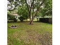 Large backyard with a fire pit, mature trees, and a wood fence at 1601 Westmoreland Ave, Charleston, SC 29412