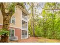 Multi-story condo building featuring private screened balconies amidst a serene backdrop of trees and lush greenery at 300 Bucksley Ln # 102, Charleston, SC 29492