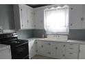 Functional kitchen with white cabinets, counters, black oven and a window above the sink at 301 Ridge St, Saint George, SC 29477