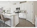 Modern white kitchen featuring an island with bar seating, stainless steel appliances, and hardwood flooring at 422 Radiant Blue Way, Summerville, SC 29486