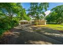 Long driveway leads to a white home with a detached garage surrounded by lush greenery at 881 Evans Rd, Charleston, SC 29412