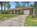 Charming brick home featuring an attached garage, front porch and long driveway surrounded by trees at 127 Cornell Dr, Ladson, SC 29456