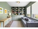 Cozy living room with custom built-in shelving, soft gray sofa, and large windows offering natural light at 1825 Crossbill Trl, Hanahan, SC 29410