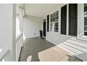 Inviting covered front porch with gray stained wood flooring and white railing, and black shutters at 2152 Pentland Dr, Charleston, SC 29412