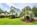 Spacious green yard with various palm trees and landscaping around the light blue two-story home at 2734 Battle Trail Dr, Johns Island, SC 29455