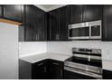 Close-up of modern kitchen featuring sleek dark cabinets, stainless steel appliances, and white subway tile backsplash at 331 Bremerton Dr, Goose Creek, SC 29445