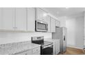 Stylish kitchen boasts gray cabinets, granite counters, stainless steel appliances, and sleek hardwood floors at 6039 Savy Ct, Ravenel, SC 29470