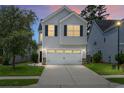Charming two-story home with a two-car garage, manicured lawn, and classic curb appeal at dusk at 8921 Skipping Rock Ln, Summerville, SC 29485