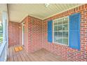 Inviting front porch featuring a brick exterior, a window with blue shutters, and decorative lighting fixtures at 100 Cicero Ct, Goose Creek, SC 29445