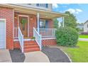 Inviting brick front porch with white railings and a decorative wreath on the wood front door at 100 Cicero Ct, Goose Creek, SC 29445
