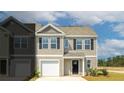 Exterior of a tan townhome features black shutters and a single-car garage, under a partly cloudy blue sky at 144 Haventree Ct, Summerville, SC 29486