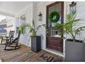 Inviting front porch with rocking chairs, a dark wood front door, and decorative plants at 2828 Wagner Way, Mount Pleasant, SC 29466