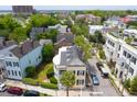 Aerial view of neighborhood showcasing yellow two-story home with double verandas and surrounding trees at 29 Smith St, Charleston, SC 29401