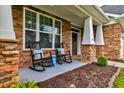 Inviting front porch with stone detailing, white columns, and comfortable rocking chairs at 314 Freeland Way, Moncks Corner, SC 29461