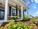 Inviting front porch with a sitting area, colorful flowers, and a South Carolina state flag at 470 Sanctuary Park Dr, Summerville, SC 29486