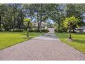 Long brick driveway leading to a beautiful home surrounded by mature trees and a well-manicured lawn at 7879 Gull Bay Dr, Awendaw, SC 29429
