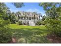 Inviting two-story home framed by lush greenery, showcasing a classic design with a welcoming front porch at 7879 Gull Bay Dr, Awendaw, SC 29429