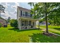 Two-story home with a well-maintained lawn, a welcoming front porch, and classic curb appeal at 8938 Planters Row Ln, Summerville, SC 29485