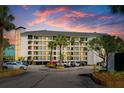Beautiful condo building exterior with palm trees, parking, and balconies with an amazing colorful sunset backdrop at 9002 Palmetto Dr # 420, Isle of Palms, SC 29451