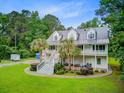 Elegant two-story home with a metal roof, double porches, mature trees, and an expansive green lawn at 142 Maxwell Rd, Summerville, SC 29483