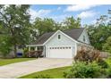 Charming light-blue single-story home with a two-car garage and a long driveway surrounded by lush landscaping at 1928 Gasque St, Johns Island, SC 29455