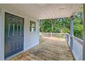 Cozy covered porch with wooden decking and classic white railing, door to interior at 208 State St, Walterboro, SC 29488