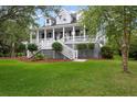 Elegant two-story home with charming porch, white railings and stairs, surrounded by a well-manicured green lawn at 2293 Beckenham Dr, Mount Pleasant, SC 29466