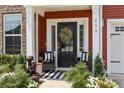 Cozy front porch featuring chairs, striped rug, potted plants, and a decorative wreath on the door at 255 Saxony Loop, Summerville, SC 29486
