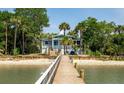 Stunning waterfront home showcasing a long private dock with sandy beach access, surrounded by mature palm trees at 2619 Buccaneer Rd, Isle of Palms, SC 29451