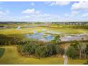 A stunning aerial view of the landscape with marsh views and a golf course in the distance under a partly cloudy sky at 27 Watroo Pt, Daniel Island, SC 29492