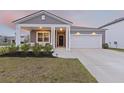 Charming single-Gathering home featuring a covered porch, attached garage, and a well-manicured lawn at 286 W Bradford Pointe Dr, Summerville, SC 29486