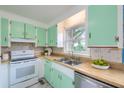 Charming kitchen offers green cabinets, stainless steel sink, and a window, blending vintage charm with modern convenience at 444 Clarine Dr, Goose Creek, SC 29445