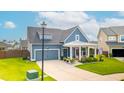 Charming home featuring a covered porch, gray siding, a well-manicured lawn, and an attached two-car garage at 627 Macintyre Cir, Summerville, SC 29486